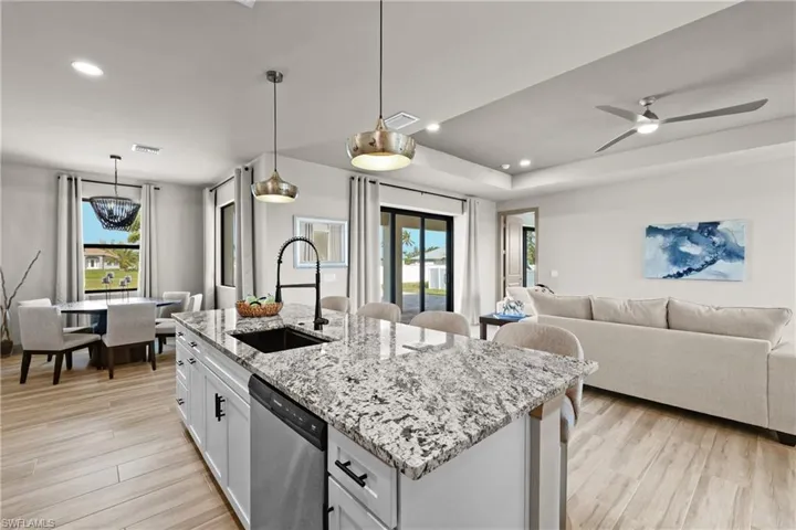 Kitchen featuring plenty of natural light, sink, stainless steel dishwasher, decorative light fixtures, and white cabinetry