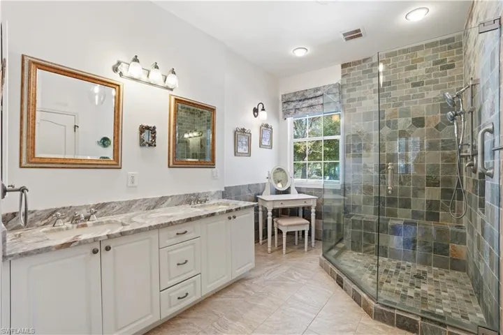 The ensuite bathroom features dual sinks, a large walk-in shower and custom light fixtures