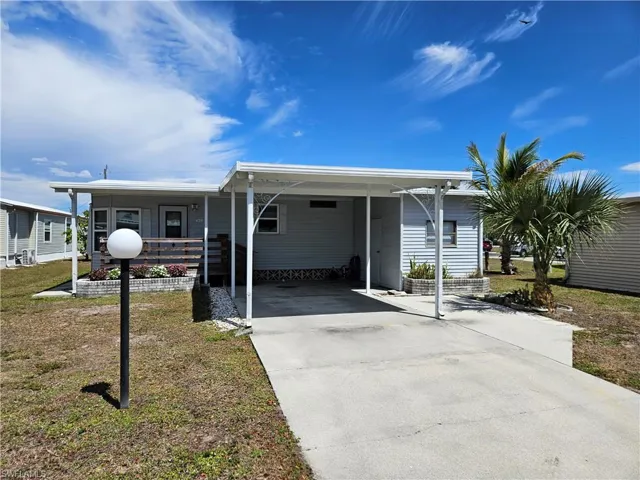 Manufactured / mobile home featuring driveway, a carport, and a front lawn