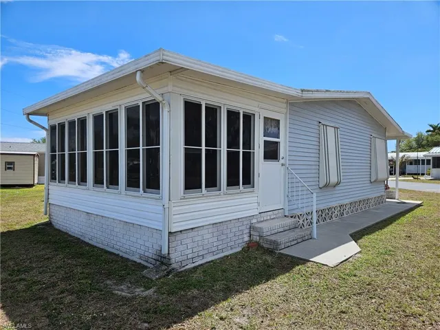 View of property exterior featuring a lawn and side entry into sunroom