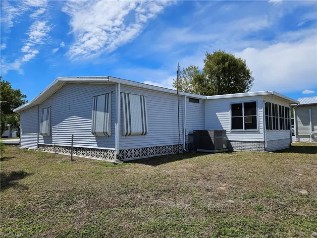 View of property exterior featuring a lawn and a cooling unit