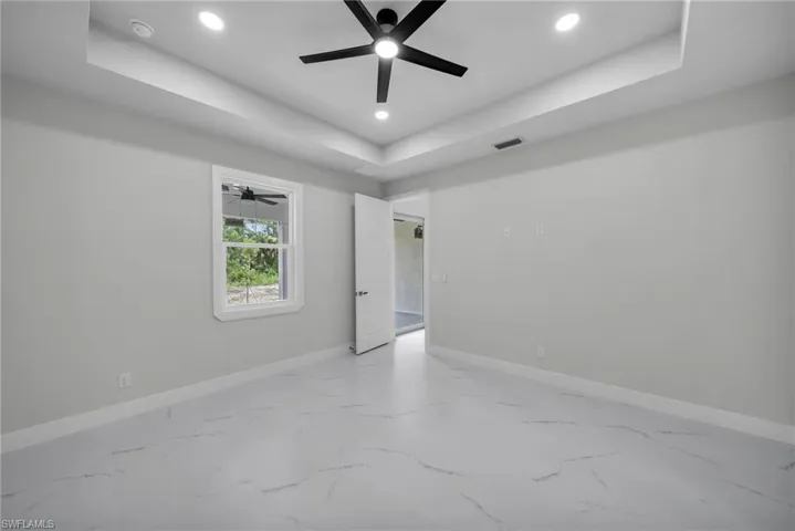 Spare room featuring ceiling fan, a raised ceiling, and tile patterned floors