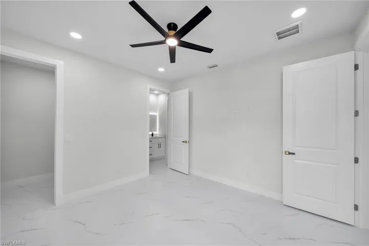 Unfurnished bedroom with ceiling fan, connected bathroom, and light tile patterned floors