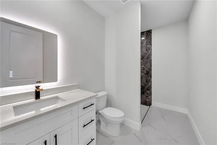 Bathroom with tile patterned flooring, toilet, vanity, and tiled shower