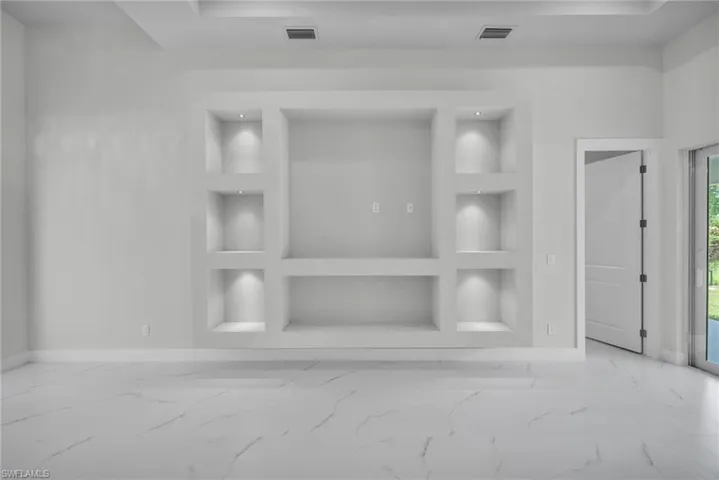 Unfurnished living room featuring built in features and light tile patterned flooring