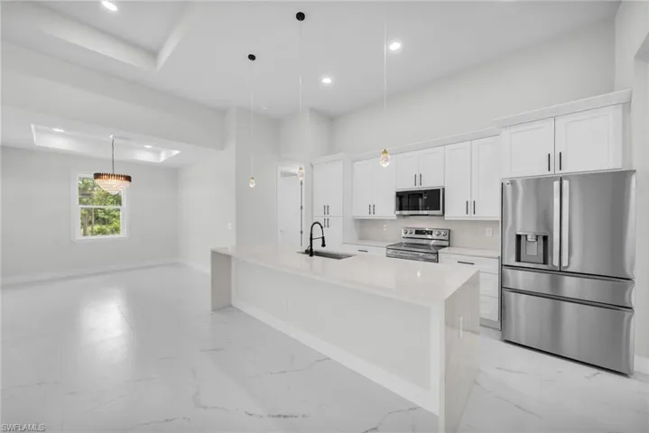 Kitchen featuring stainless steel appliances, sink, light tile patterned floors, and an island with sink
