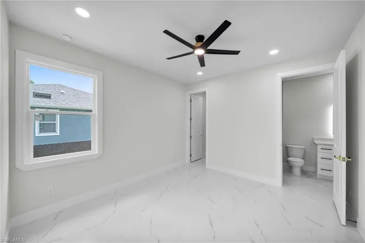 Unfurnished bedroom featuring ceiling fan, connected bathroom, and light tile patterned floors