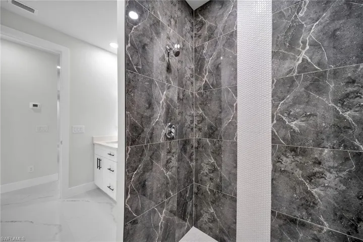 Bathroom with tiled shower, tile patterned floors, and vanity