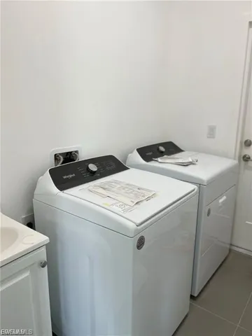 Laundry room featuring tile patterned flooring and washing machine and clothes dryer