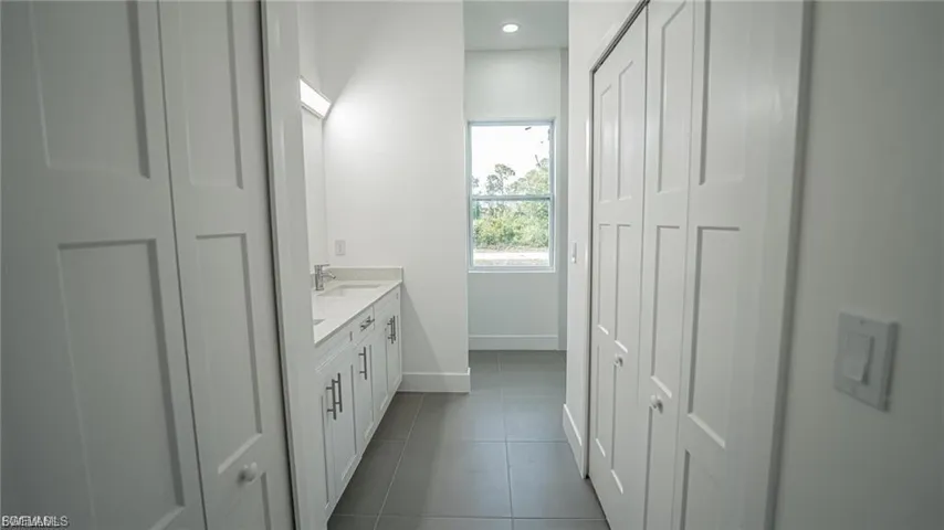 Bathroom with double vanity, a closet, dark tile patterned floors, and recessed lighting
