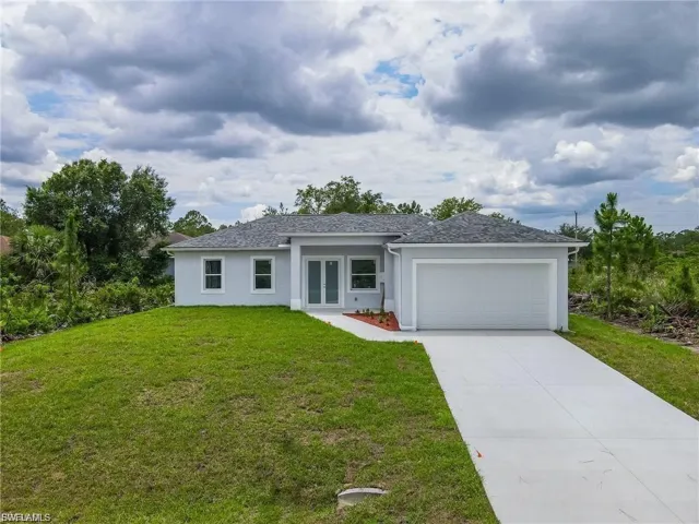 View of front of home with an attached garage, stucco siding, concrete driveway, a front yard, and roof with shingles
