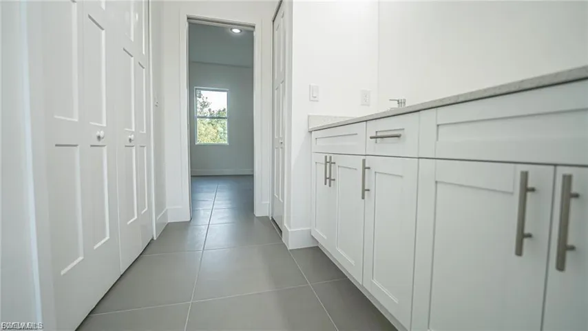 Hallway with tile patterned floors and baseboards