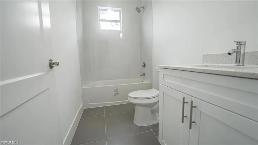 Bathroom featuring vanity, dark tile patterned floors, and tub / shower combination