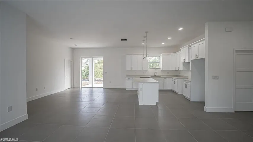 Kitchen featuring white cabinets, a center island, recessed lighting, open floor plan, and light countertops