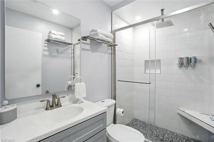 Contemporary bathroom featuring a spacious glass-enclosed shower with pebble flooring, a rain shower head, and a built-in shower niche