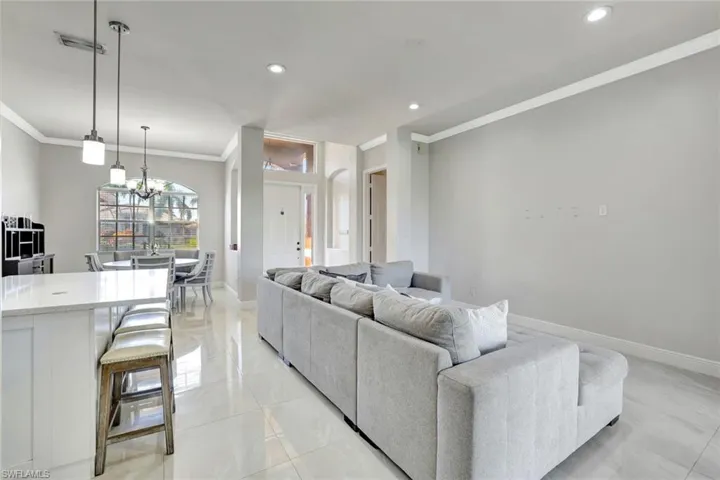 Living area with crown molding, recessed lighting, a chandelier, and light tile patterned floors