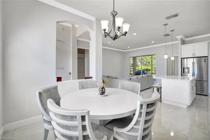 Dining area featuring ornamental molding, a chandelier, arched walkways, and recessed lighting