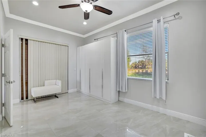 Unfurnished bedroom with crown molding, a ceiling fan, light marble finish flooring, and recessed lighting