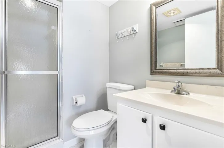 Bathroom with a shower with shower door, oversized vanity, and toilet