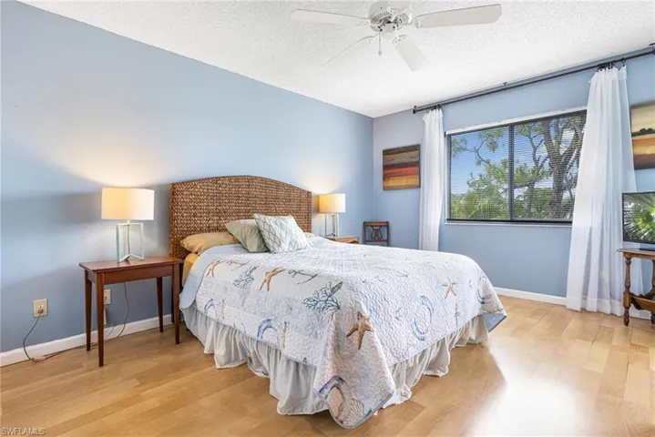 Bedroom featuring light hardwood / wood-style floors, a textured ceiling, and ceiling fan