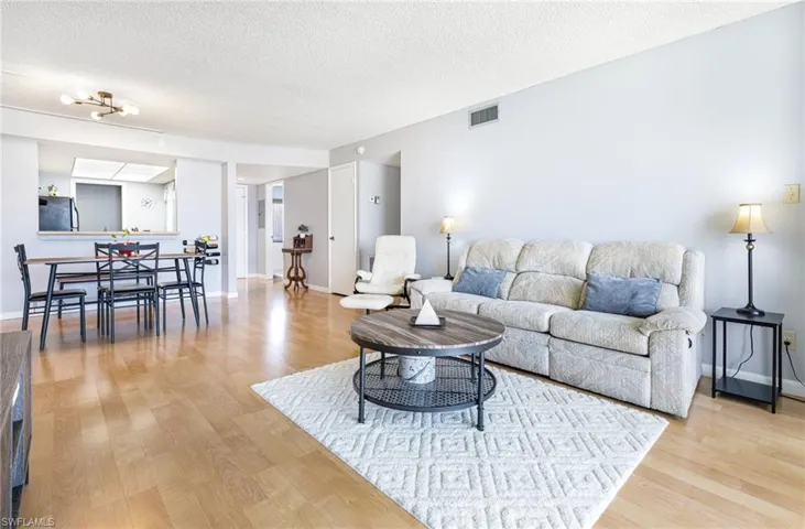 Living room featuring light hardwood / wood-style floors, a textured ceiling, and an inviting chandelier