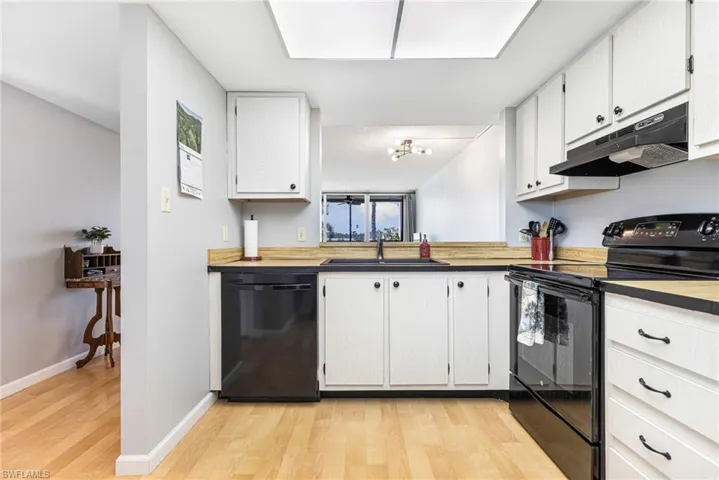 Kitchen featuring white cabinets, black appliances, sink, and light hardwood / wood-style floors