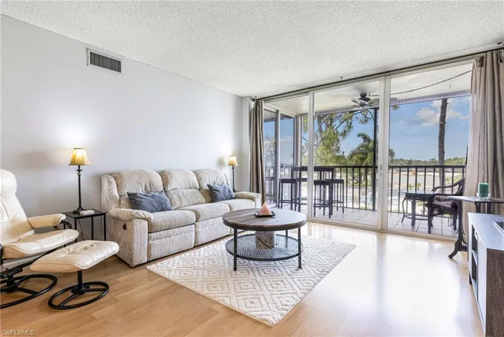 Living room with expansive windows, light hardwood / wood-style floors, and a textured ceiling