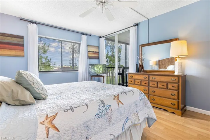 Bedroom featuring ceiling fan, access to exterior, multiple windows, and light wood-type flooring