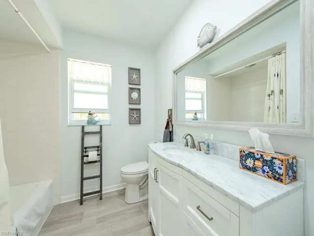 Full bath featuring baseboards, toilet, vanity, and shower / bathtub combination with curtain