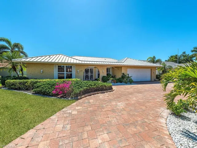 Single story home with decorative driveway, a front yard, stucco siding, and an attached garage