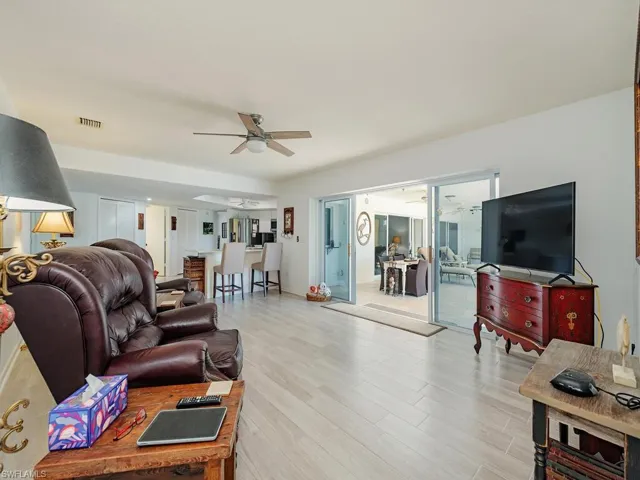 Living area featuring light wood finished floors, visible vents, and ceiling fan