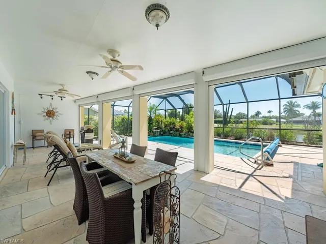 View of patio featuring glass enclosure, outdoor dining area, an outdoor pool, and ceiling fan