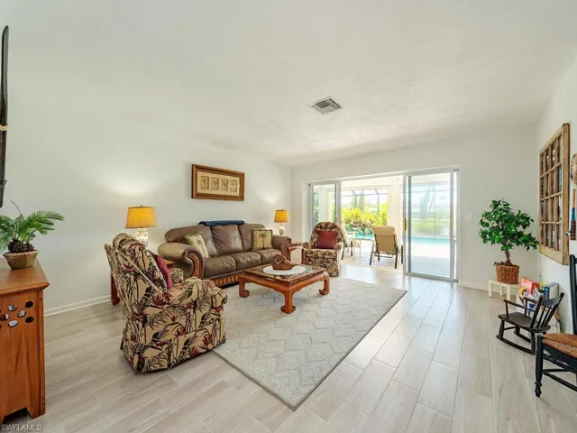 Living area featuring a textured ceiling, baseboards, light wood-style flooring, and visible vents