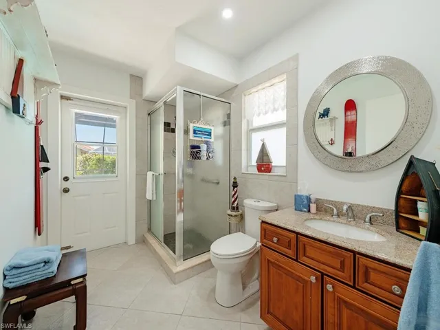 Bathroom with a shower stall, a wealth of natural light, vanity, and tile patterned floors