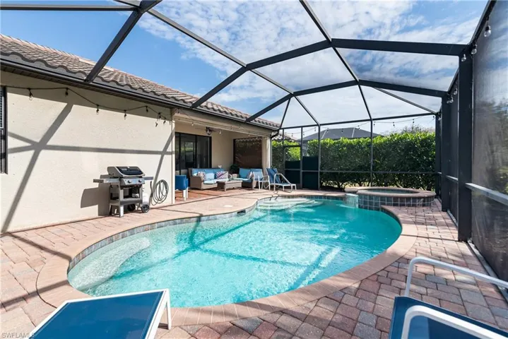View of swimming pool featuring a sunroom, a patio, glass enclosure, area for grilling, and a pool with connected hot tub