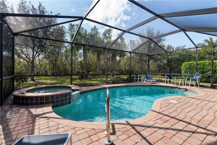 View of swimming pool featuring glass enclosure, a sunroom, a pool with connected hot tub, and a patio