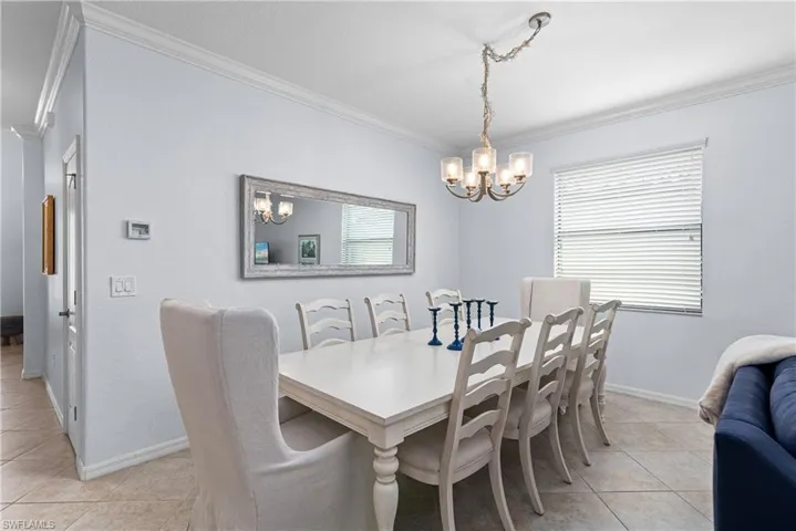 Dining area with light tile patterned flooring, a chandelier, crown molding, and plenty of natural light