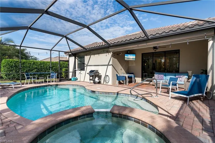 View of swimming pool with a sunroom, a patio area, a lanai, a pool with connected hot tub, and grilling area