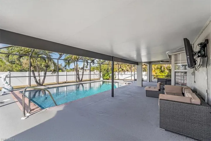 View of pool featuring an outdoor living space, a patio, and glass enclosure