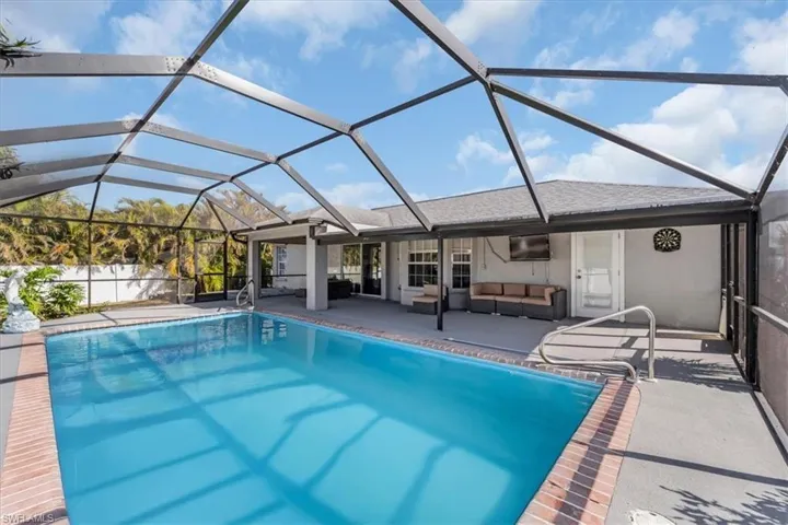 View of swimming pool with an outdoor living space, a patio, and a lanai