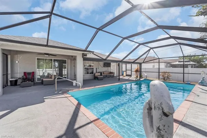View of swimming pool featuring ceiling fan, a lanai, an outdoor living space, and a patio