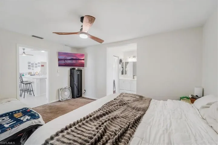Master Bedroom featuring ensuite bathroom, carpet floors, and ceiling fan