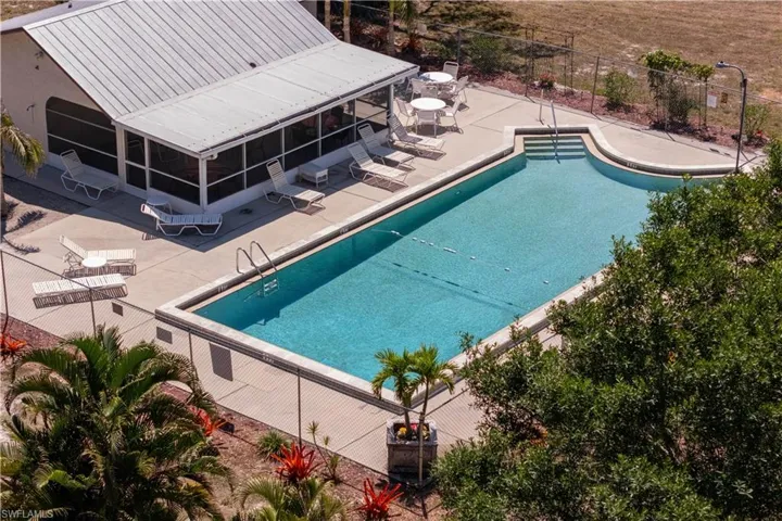 Community pool with fence, a patio, and a sunroom