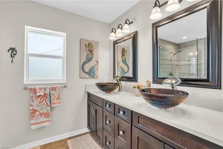 Bathroom featuring dual bowl vanity, a tile shower, and hardwood / wood-style flooring
