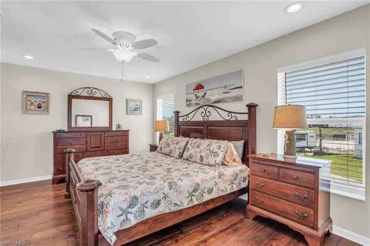Bedroom with ceiling fan, multiple windows, and dark hardwood / wood-style flooring