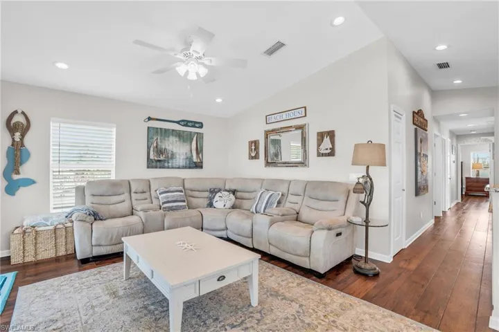 Living room with vaulted ceiling, hardwood / wood-style floors, and ceiling fan
