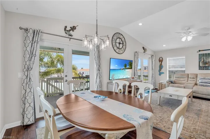 Dining area featuring dark hardwood / wood-style floors, ceiling fan with notable chandelier, and lofted ceiling