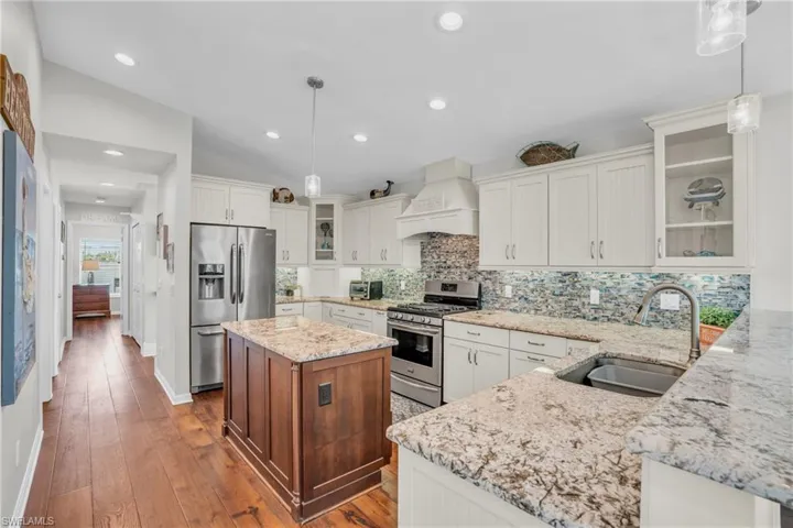 Kitchen with tasteful backsplash, custom exhaust hood, sink, lofted ceiling, and appliances with stainless steel finishes