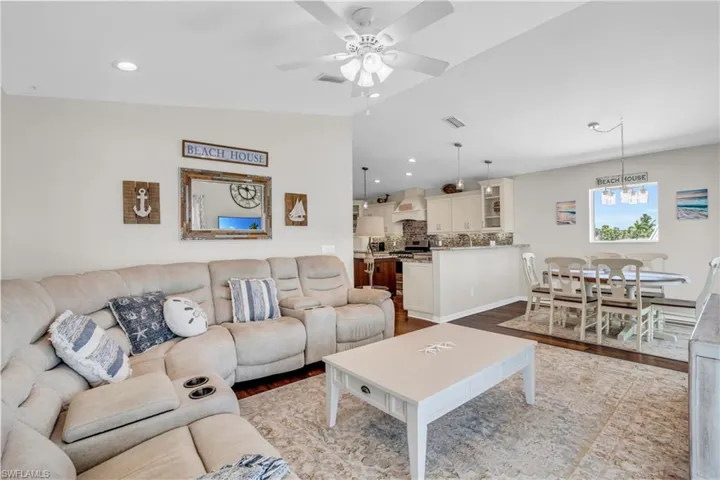 Living room featuring lofted ceiling, wood-type flooring, and ceiling fan