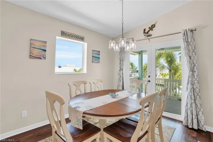 Dining room featuring dark wood-type flooring, an inviting chandelier, and french doors
